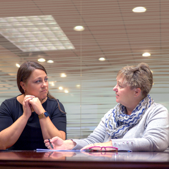 OMANI HOPE CONSULTING – TWO WOMEN FACING EACH OTHER SITTING AT TABLE